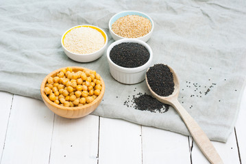 cooked chick pea and sesame seeds, hummus ingredients on cotton canvas, white wooden table background