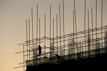 Construction workers work in silhouette at sunset