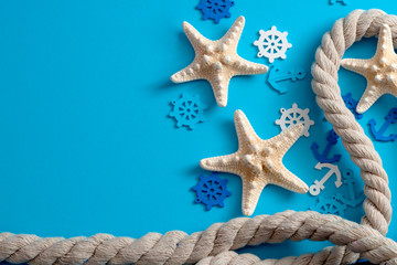 Fototapeta na wymiar Beach vacation and seaside travel concept theme with rope, starfish, helm and anchor isolated on blue background with copy space