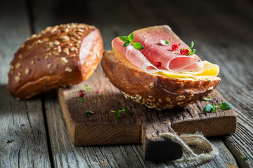 Roll with ham and cheese for breakfast on wooden table