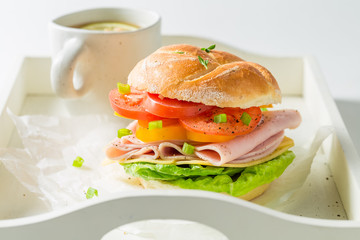 Tasty sandwich with cheese, ham and tea on white table