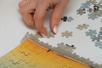 Hands of two women which assemble world map puzzle on table