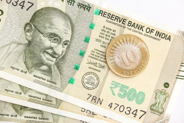 Close up view of brand new indian 500 rupees banknotes and coin on white background.