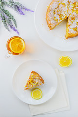 Slice of lemon pie with a cup of tea on a white table