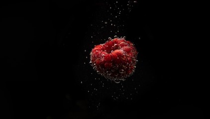 Raspberry berry with bubbles of sparkling water isolated on black background.