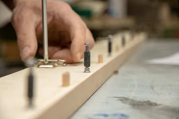 The furniture maker assembles the Cabinet, he tightens the screws with a screwdriver .