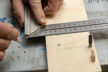 The furniture maker puts a marking on furniture preparation by means of a pencil and a joiner's square.