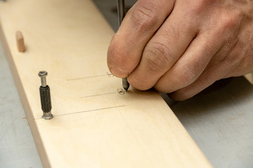 The furniture maker puts a marking on a furniture preparation by means of the special tool.