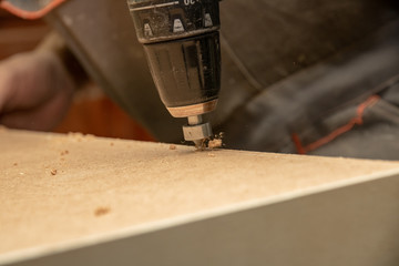 The furniture maker drills furniture blanks with a cordless drill.