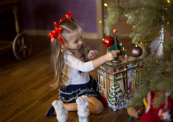 girl decorates Christmas tree at home