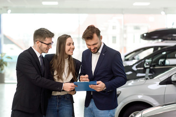 Cheerful buyers with car dealer in shop