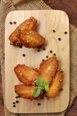 Beautiful plate fried chicken wings on wooden tray with garlic and pepper, selective focus and free copy space. Clean food good taste concept.