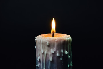colored candle with drips of wax burns in the dark