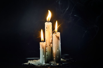 Group of white candles burning in the dark