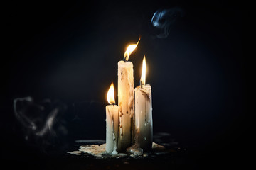 Group of white candles burning in the dark