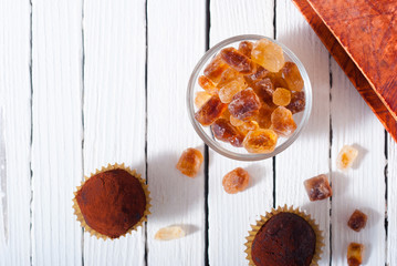 herbal tea, brown sugar, chocolate truffles and an old book on white wooden table