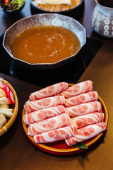 Premium Rare Slices Kurobuta (Black Pig) pork with high-marbled texture on circle wooden plate served for Sukiyaki and Shabu.