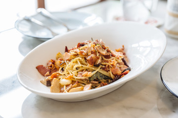 Dried Spaghetti Chili Bacon served in white bowl plate on marble table.