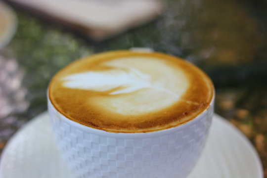 white coffee cup with blur topping of latee art and background blur