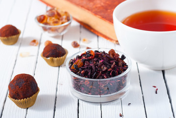 herbal tea, brown sugar, chocolate truffles and an old book on white wooden table