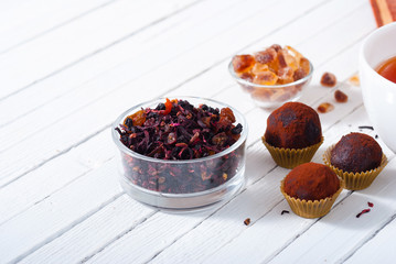 herbal tea, brown sugar, chocolate truffles and an old book on white wooden table