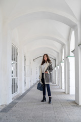 A girl in a light sheepskin coat at the colonnade