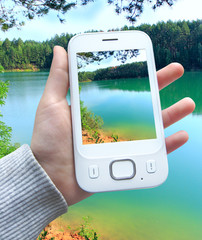 Smartphone with image of forest lake on screen in human hand