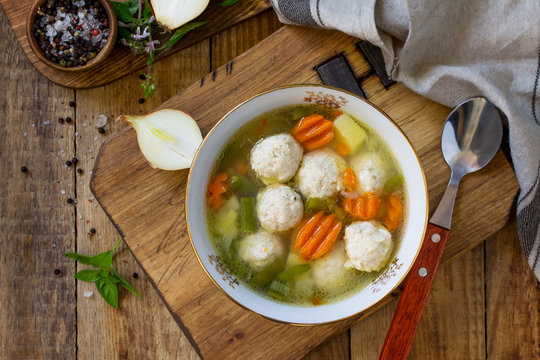 The concept Diet menu. Healthy soup with vegetables and chicken meatballs in a bowl on wooden table in rustic style. Top view flat lay background. Copy space.