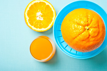 oranges with manual juicer like preparation of orange juice juice in glass  over aquamarine background 