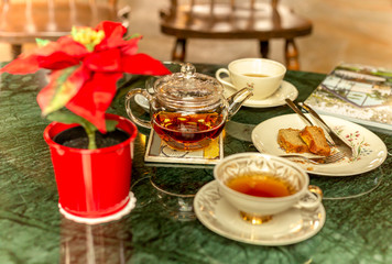 Fototapeta na wymiar Tea in cup and teapot with piece of cake on marble table.