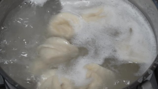 Pelmeni (meat dumplings) being boiled in pan. 8x fast