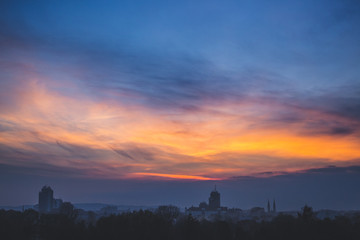 Dim winter twilight. Clouds at sunset over dark industrial town.