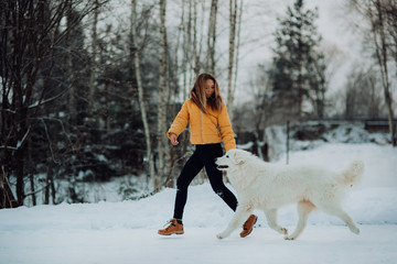 girl teaches how to right run a dog in winter park. The girl with the Maremma . Forest on background