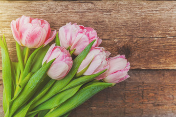 Spring greeting card. Bouquet of fresh light pastel pink tulips flowers on wooden background. Happy holiday easter mother day anniversary valentine day birthday concept. Flat lay top view copy space