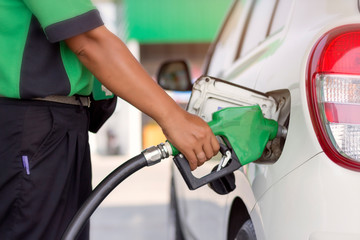 white car refueling gasoline by auto dispenser nozzle at petrol station with warm sunlight