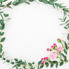 Flower frame of pink roses and eucalyptus branches on white background. Flat lay, top view