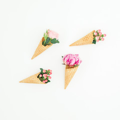 Concept with pink peonies, roses petals and waffle cones on white background. Flat lay, top view