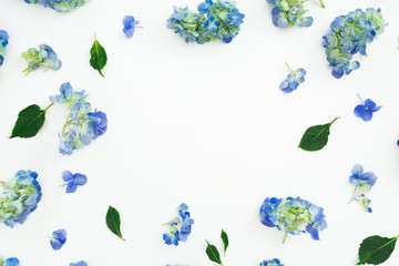 Floral frame of blue hydrangea flowers and leaves on white background. Flat lay, top view. Floral background