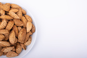 Almonds in white porcelain plate and surface is isolated white