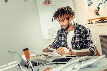 Bearded interior designer with dreadlocks holding ruler in his hand
