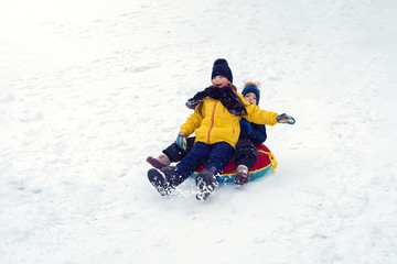 Fototapeta na wymiar happy children sledding tubing. brother and sister play together in winter. children slide down the hill. kids laugh and scream