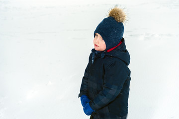 Fototapeta na wymiar portrait of a sad little boy. offended child is crying. in a blue folder and jacket, wearing mittens in the