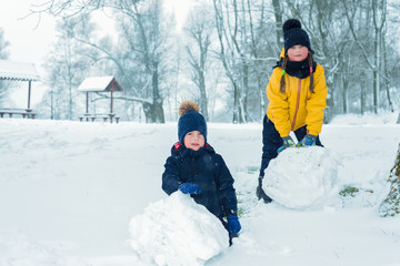 Fototapeta na wymiar portrait of brother and sister. little boy and girl make snowman in winter.