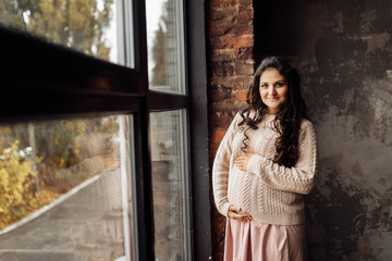 Beautiful pregnant woman in rose sweater