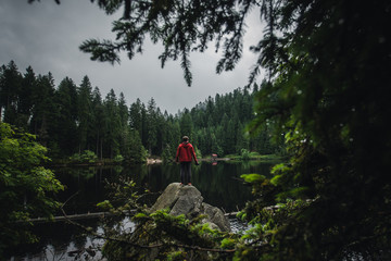 Man in a red jacket exploring a hidden lake