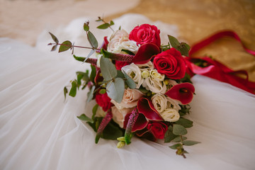 Beautiful wedding bouquet lies on a wedding dress. Wedding day. Wedding preparation.