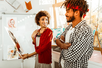 Bearded artist presenting portrait of his appealing stylish girlfriend