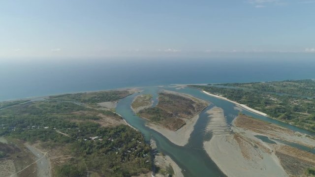 Aerial view river flowing into the sea in Philippines,Luzon. tropical landscape with sandy coast and river among farmer fields flowing into the blue ocean