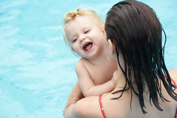 Mother and baby enjoying the day at the pool, summer outdoor activity, learning to swim