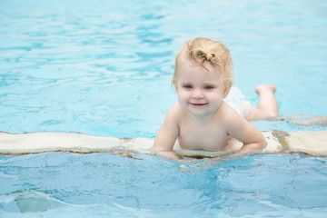 Fototapeta na wymiar Portrait of a happy baby girl in the swimming pool 